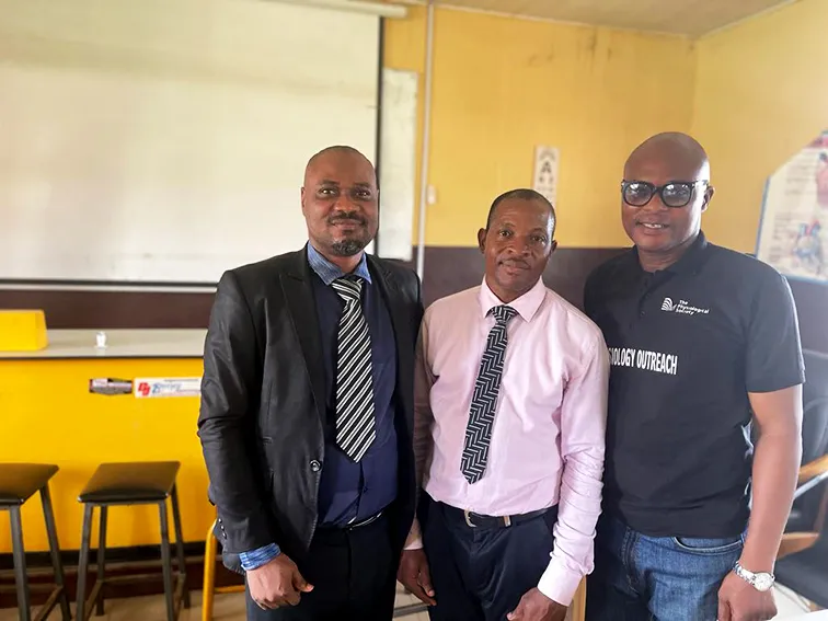 Johnson Olowe is pictured in a classroom environment standing between two men. On the left is Dr Victor Emojevwe - Acting HOD, while on the right is Dr Adeniran Akinola, immediate past HOD.